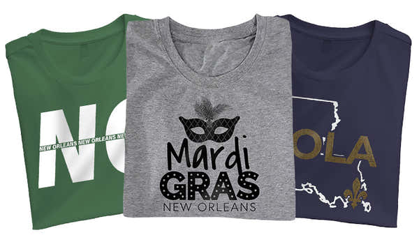 Three New Orleans-themed t-shirts; black with a fleur-de-lis and 'NOLA,' heather gray with a jazz trumpet and 'New Orleans' text, and navy with a colorful Mardi Gras mask.