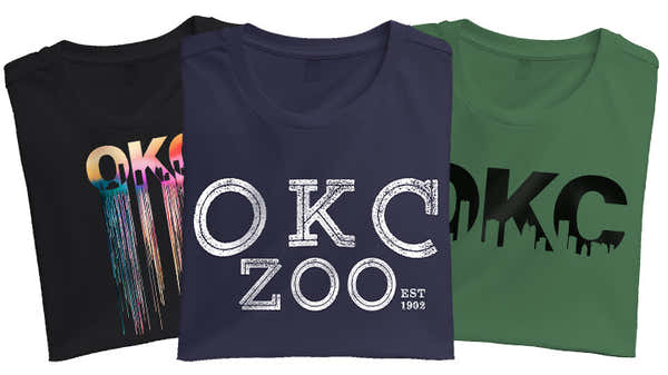 A banner featuring three folded t-shirts with 'OKC' designs: one with a colorful drip pattern, one with a distressed 'OKC ZOO EST 1902', and one with a silhouette skyline, from the 'Oklahoma City' collection.